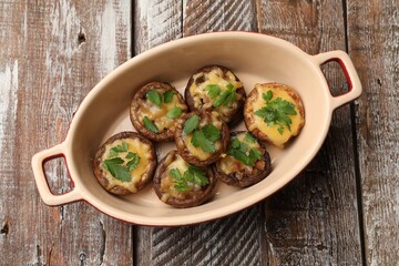 Delicious stuffed mushrooms with melted cheese and parsley in baking dish on color wooden table, top view