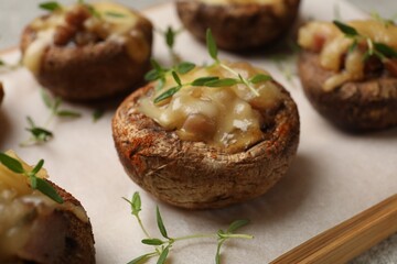 Delicious stuffed mushrooms with melted cheese and thyme on table, closeup