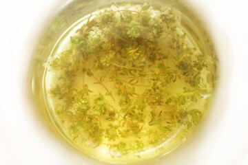 Herbal thyme tea in a glass jar, shallow depth of field.