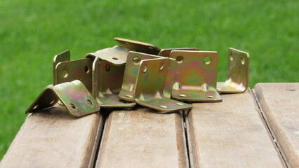 Various metal brackets arranged on a wooden surface with a green grass background