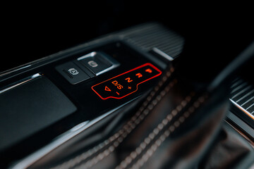 The photo shows the center console, buttons and the automatic sports transmission lever. Black premium leather, steering wheel. Luxury car interior design. Marketing, advertising or press articles.