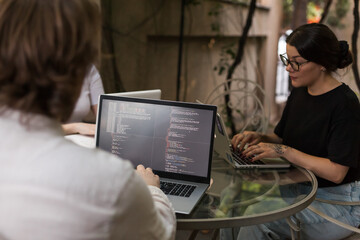 Three software developers brainstorming in a modern office. Team coding session with laptops...