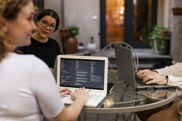 Three software developers brainstorming in a modern office. Team coding session with laptops...