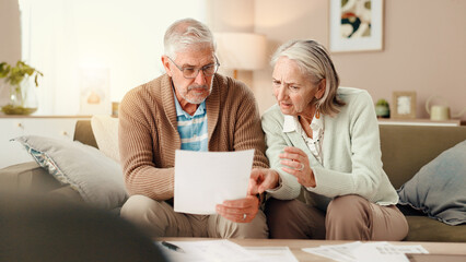 Senior couple, finance and discussion with documents on sofa for budget, expenses or bills at home....