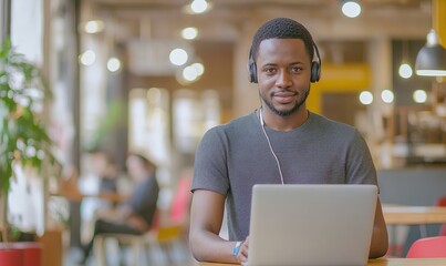 Fototapeta premium A man wearing headphones is sitting at a table with a laptop