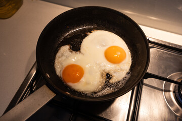 Two fried eggs on the frying pan.