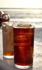 Pouring cola drink on glass with ice cubes