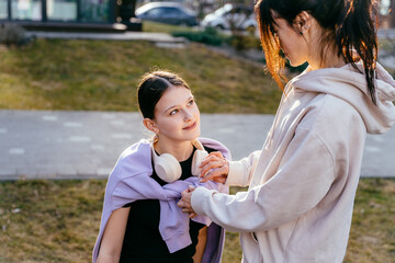 Caring mother in her 40s adjusting teenage daughter s sweatshirt outdoors