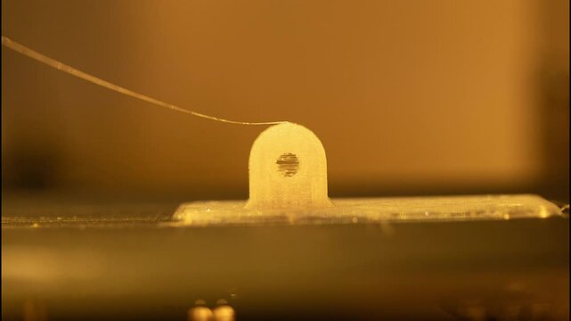 3D printer creating a new layer of material on a flat surface with focused nozzle and soft background. Timelapse footage.