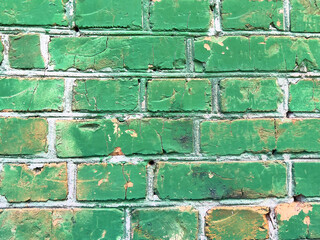 Old brick wall with chipped green paint texture. 