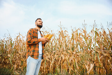 Happy young farmer or agronomist in corn field. Organic farming and food production