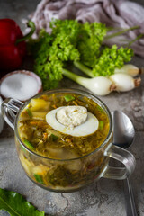 Hearty dinner: soup with sorrel and egg in a transparent plate close-up. Hot soup with sorrel for lunch. Close-up. Vertical photo