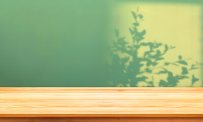 Empty wood counter table top on green concrete wall background with light and branch shadow on surface in vintage design for product mockup display presentation backdrop