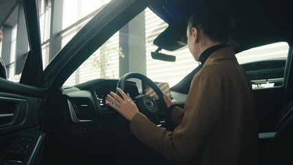 A satisfied, happy woman client sitting behind the wheel of a new car. Concept a joyful moment of car ownership.