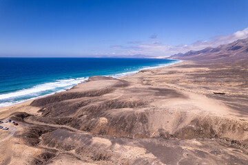 Aerial view of ocean waves and rocky shore near Playa de Cofete