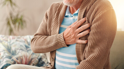 Elderly man, hands and sofa with chest pain for medical emergency or cardiac arrest at home....