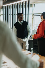 A diverse group of business people are discussing project ideas in a sunlit, modern office setting. The collaborative atmosphere showcases teamwork and innovative thinking among employees.