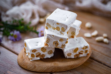 Sweet dessert: nougat with hazelnuts on a wooden table. Close-up