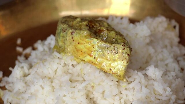 Close-up of delicious Shorshe Ilish (Hilsa fish curry with mustard paste) served with rice. Popular Bengali dish.