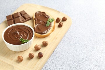 Tasty chocolate spread, toast, hazelnuts and mint on grey textured table, closeup. Space for text