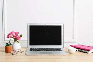 Fototapeta premium Workplace with laptop and beautiful flowers in office