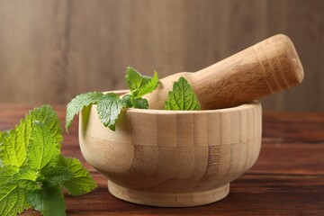 Fresh lemon balm leaves, pestle and mortar on wooden table, closeup