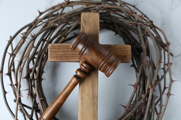 Judge's gavel, wooden cross and crown of thorns on white marble table, top view