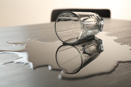 Overturned glass and spilled water on table