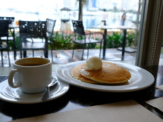 Breakfast with pancakes and coffee in cafe with harbor view in Manila, Philippines. Cozy morning scene with food and blurred city background. Perfect for travel, lifestyle, and editorial use.