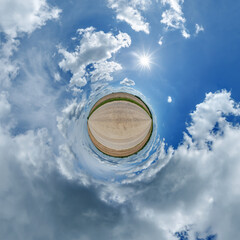 simple little tiny planet without buildings in blue sky with sun and beautiful clouds. Transformation of spherical panorama 360 degrees. Spherical abstract aerial view. Curvature of space.