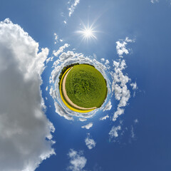 simple little tiny planet without buildings in blue sky with sun and beautiful clouds. Transformation of spherical panorama 360 degrees. Spherical abstract aerial view. Curvature of space.