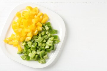 Pieces of fresh colorful bell peppers on white wooden table, top view. Space for text