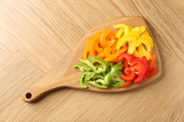Slices of fresh colorful bell peppers on wooden table, top view
