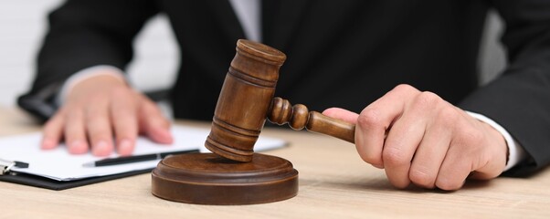 Judge with gavel working at desk indoors, closeup