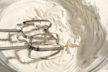 Whisks and whipped cream in bowl on table, top view