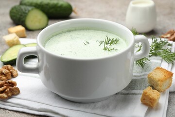 Tasty cucumber soup with dill, croutons, walnuts and vegetables on grey table, closeup