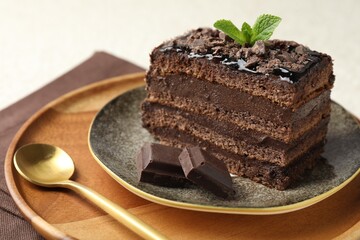 Piece of delicious chocolate cake with mint on table, closeup