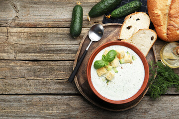 Tasty cucumber soup with croutons and basil served on wooden table, flat lay. Space for text
