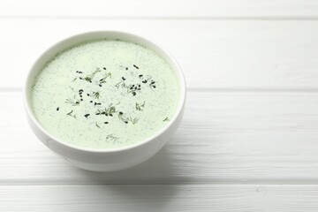 Tasty cucumber soup with dill and sesame seeds on white wooden table, closeup. Space for text