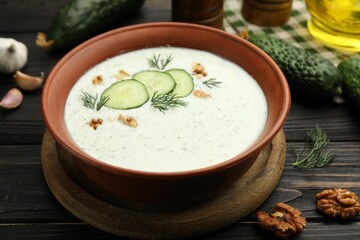 Tasty cucumber soup with dill, walnuts and ingredients on wooden table, closeup