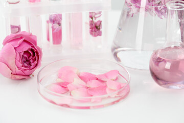 Making luxury perfume. Essential oils in glassware and flowers on white table, closeup