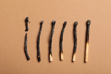 Burnt matches on beige background, flat lay