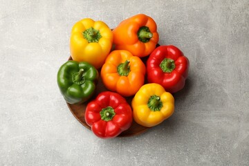 Fresh colorful bell peppers on gray textured table, top view