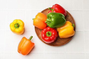 Fresh colorful bell peppers on white tiled table, flat lay