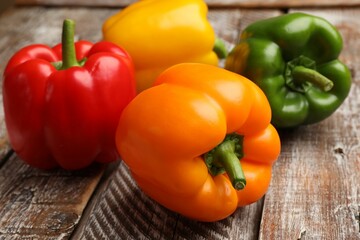Fresh colorful bell peppers on wooden table, closeup