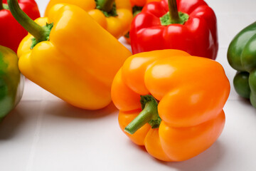 Fresh colorful bell peppers on light table, closeup