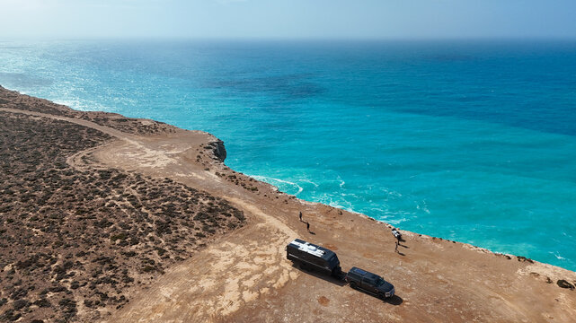 Car and caravan parked up on the edge of cliffs by the ocean
