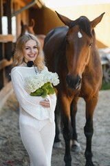 Beautiful model girl stands in a long dress with a horse