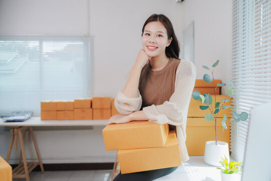 Young asian woman entrepreneur, small business owner, working at home office, packaging and delivery situation, many cardboard boxes, startup sme business concept