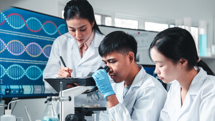 Fototapeta premium Group of young scientists in lab coats collaborate in a high-tech laboratory, analyzing samples through a microscope and documenting results, symbolizing innovation, teamwork, and modern research.